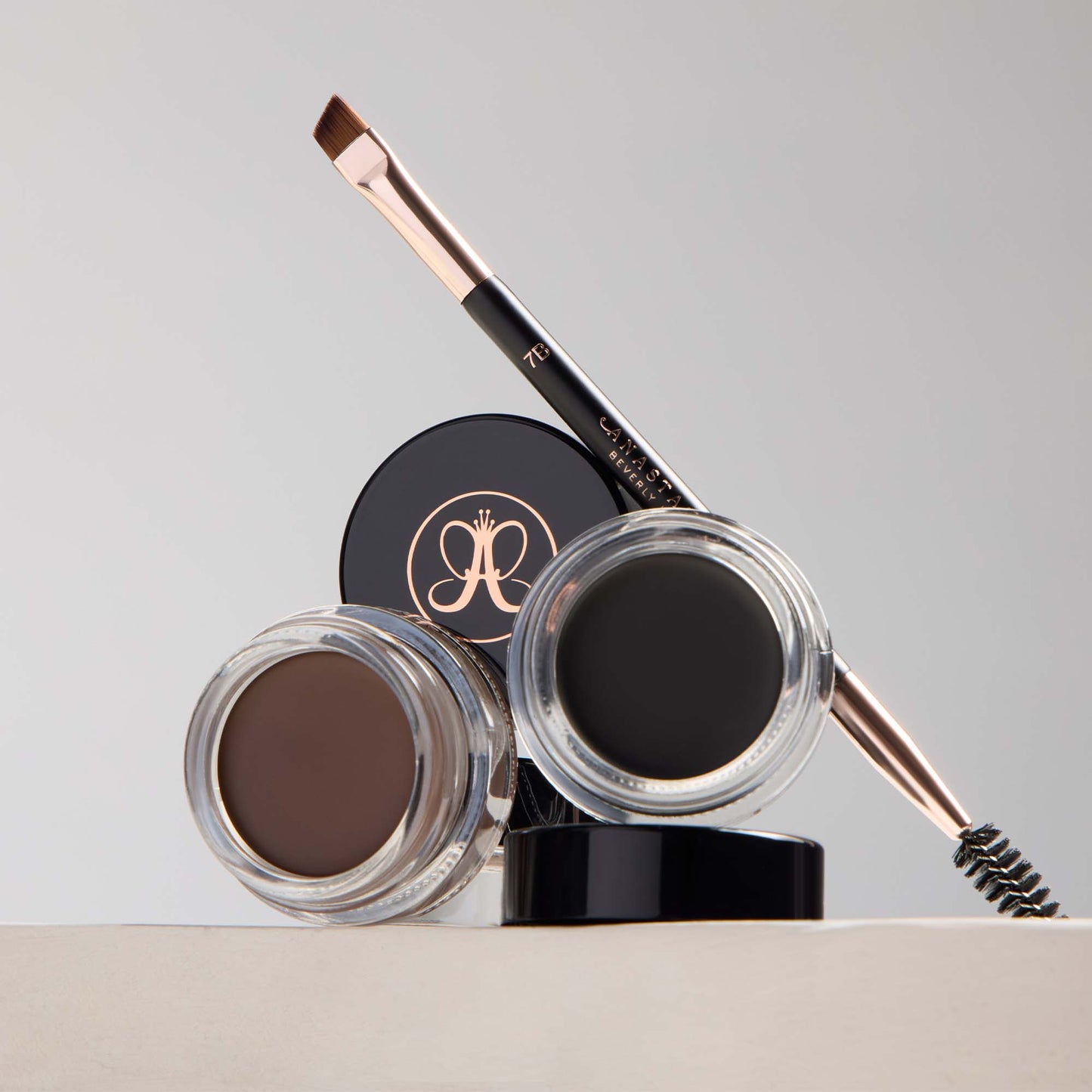 Anastasia Beverly Hills DIPBROW® Pomade in a sleek jar, displayed alongside brow tools and swatches on a neutral background.